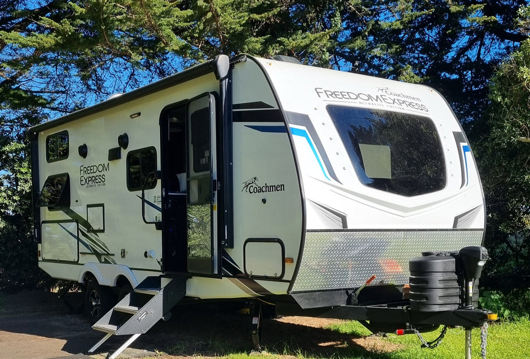 Camper parked on a grassy area with trees in the background