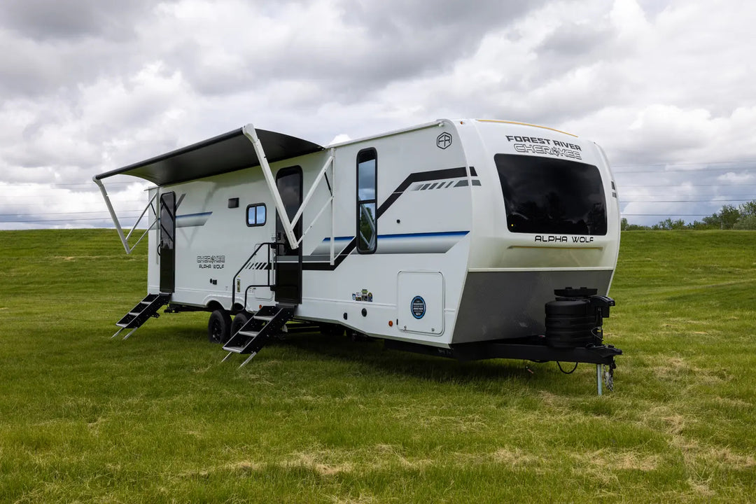 White caravan with extended awning on a grassy field under a cloudy sky