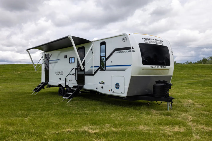 White caravan with extended awning on a grassy field under a cloudy sky