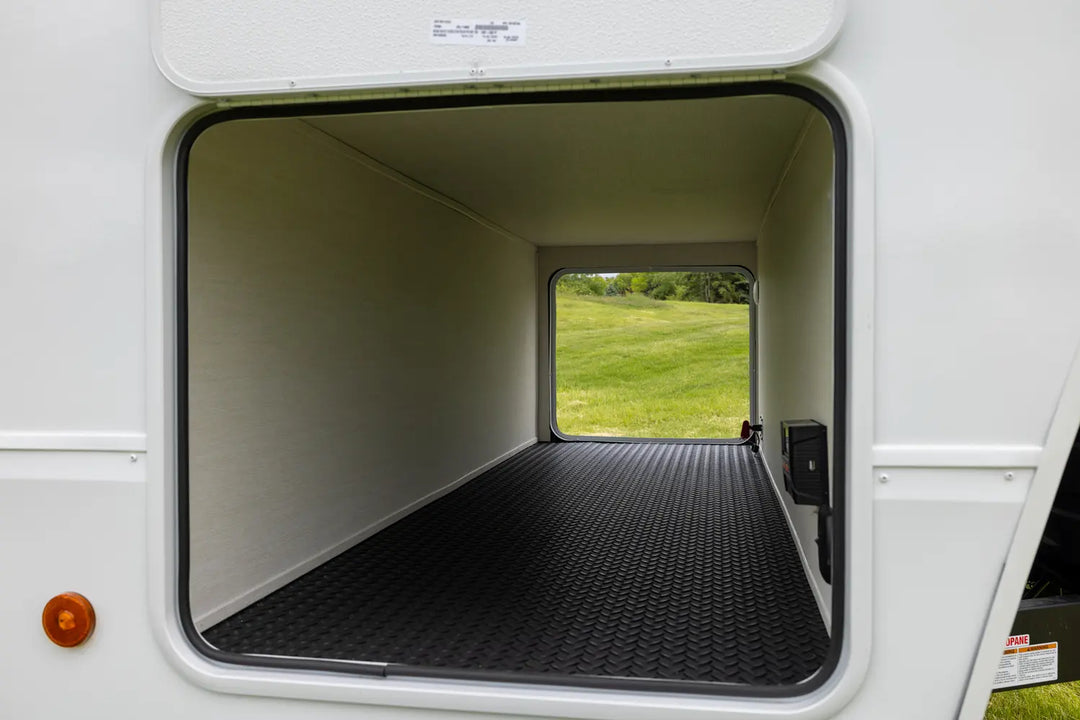 Open door of a recreational vehicle showing a grassy field outside