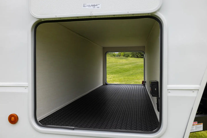 Open door of a recreational vehicle showing a grassy field outside
