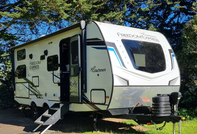 Camper parked on a grassy area with trees in the background