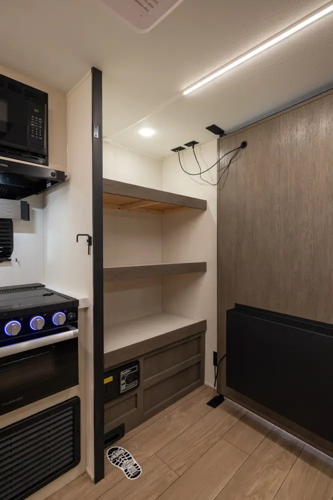 Compact kitchenette with shelves and appliances in a small living space.