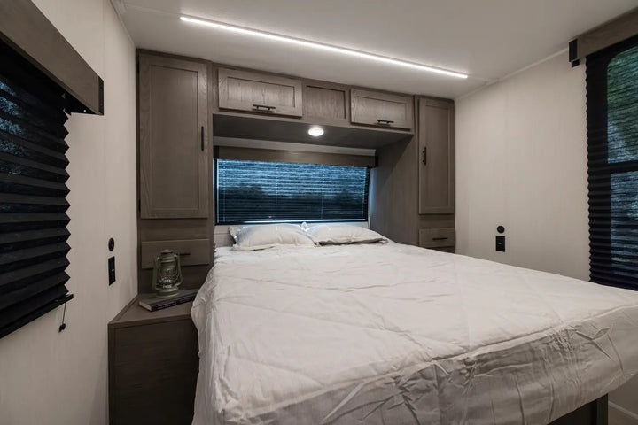 Bedroom interior with a bed, cabinets, and a window.