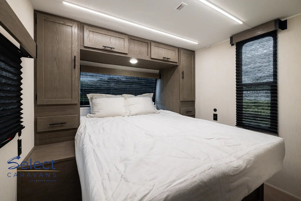 Compact bedroom with a bed, cabinets, and windows in a small living space.
