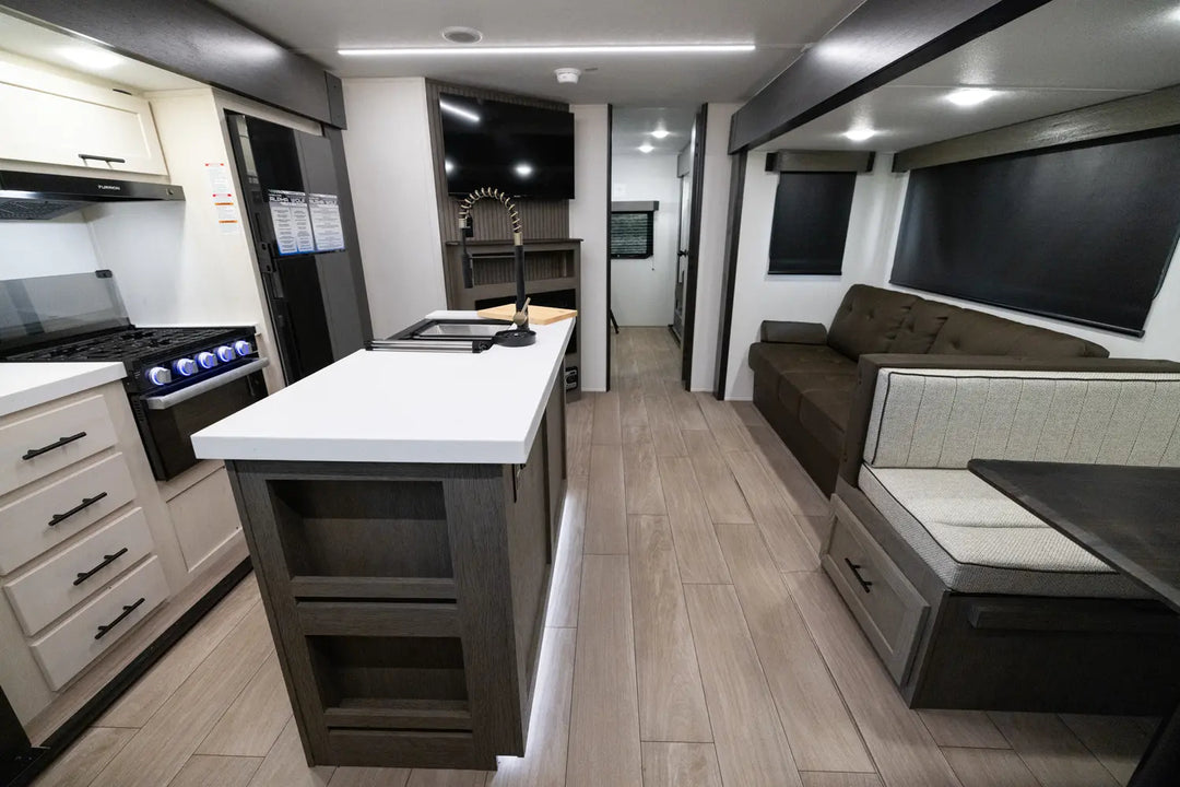 Modern RV interior with kitchen, living area, and entertainment system.
