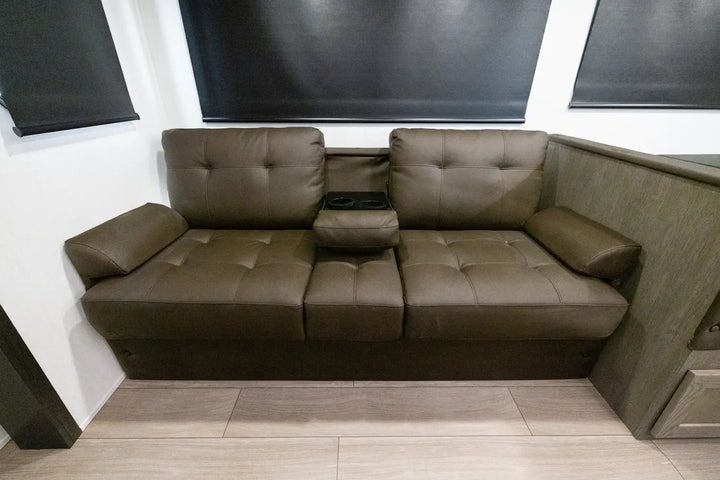 Brown leather sectional sofa in a room with wooden flooring and a window.