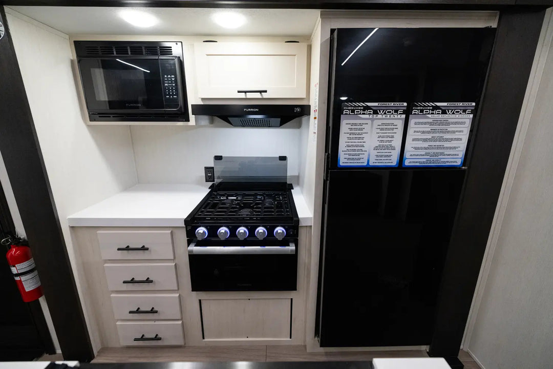Compact kitchen with black appliances including a refrigerator, stove, and microwave.