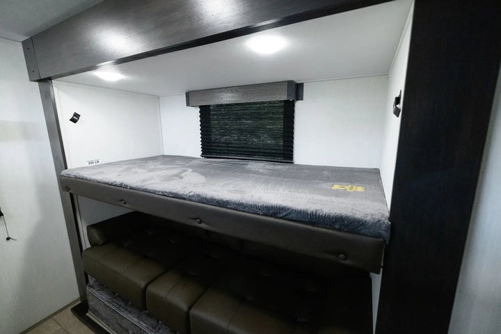 Bunk bed inside a vehicle with storage compartments below in a compact living space.