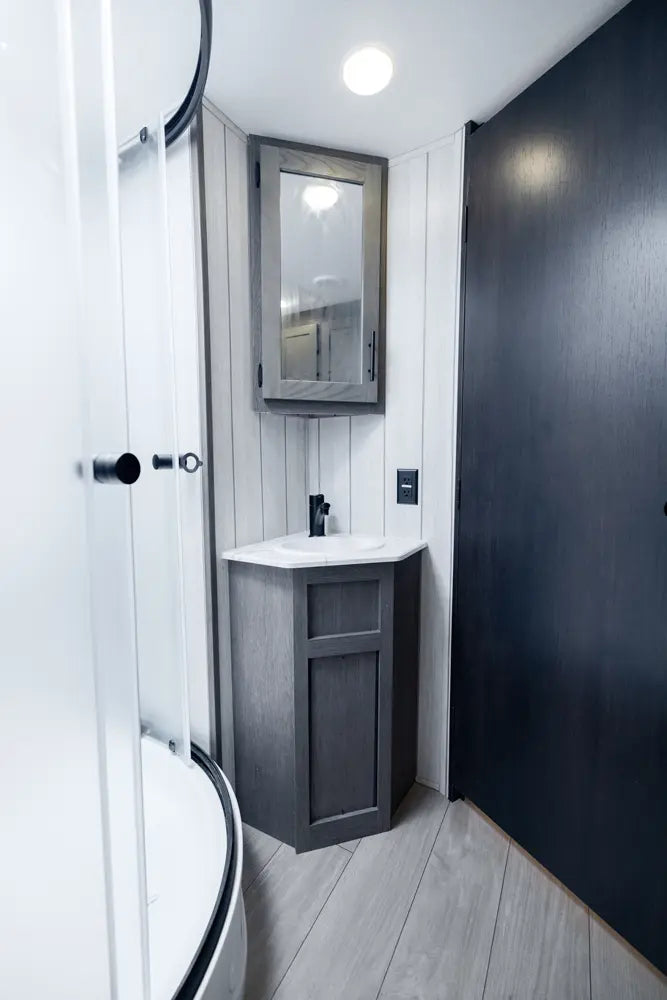 Bathroom with a vanity unit, mirror, and shower area.