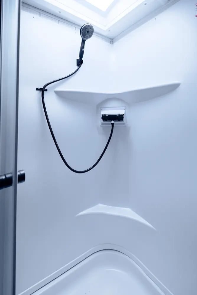 Shower head mounted on a white wall with a black hose in a compact bathroom setting.