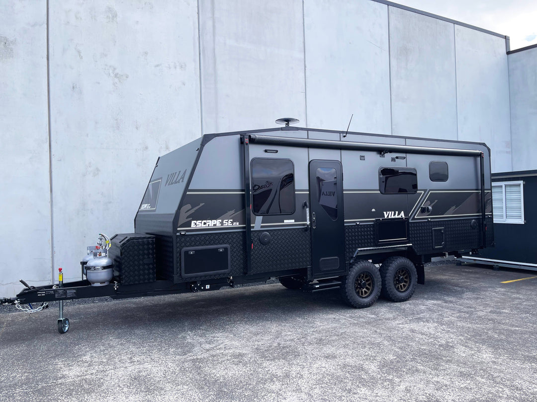 Black Villa caravan parked in front of a gray building