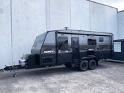 Black Villa caravan parked in front of a gray building