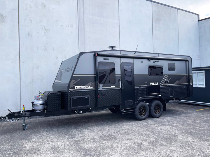Black Villa caravan parked in front of a gray building
