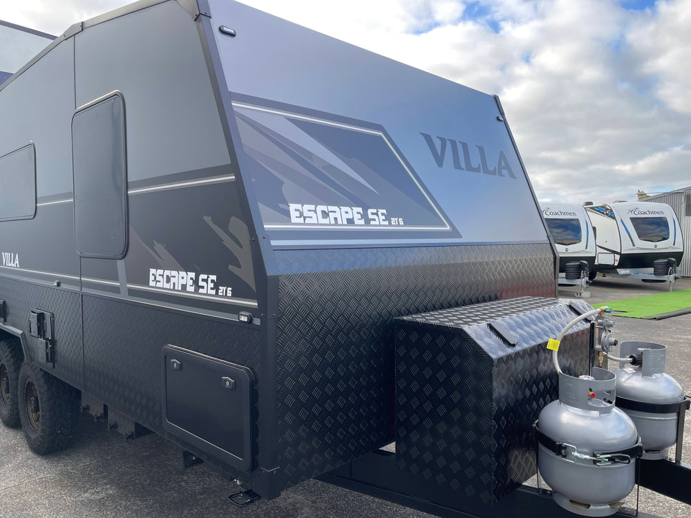 Black VILLA Escape SE caravan parked outdoors with a cloudy sky.