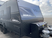 Black VILLA Escape SE caravan parked outdoors with a cloudy sky.