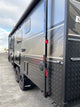 Side view of a large recreational vehicle with a textured door and visible branding.