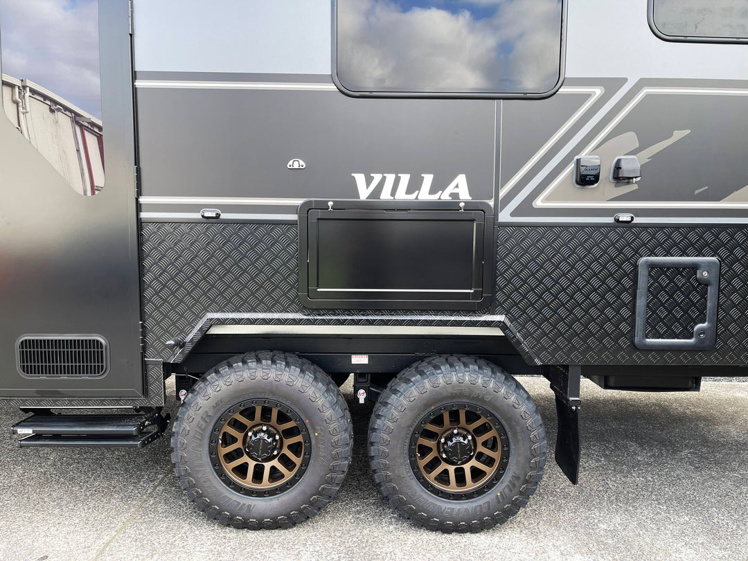Black and gray caravan with 'Villa' branding on a cloudy day