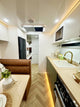 Modern kitchen and living area inside a vehicle with wooden floor and white walls.