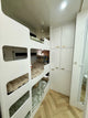 Triple Bunk beds in a compact living space with cabinets and a mirror.