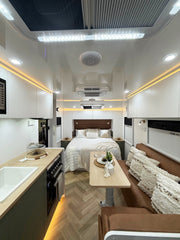 Modern RV interior with kitchen, dining area, and bedroom.