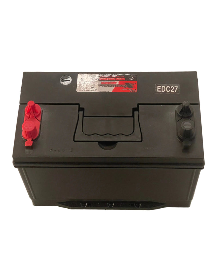 Black battery with red terminals on a white surface