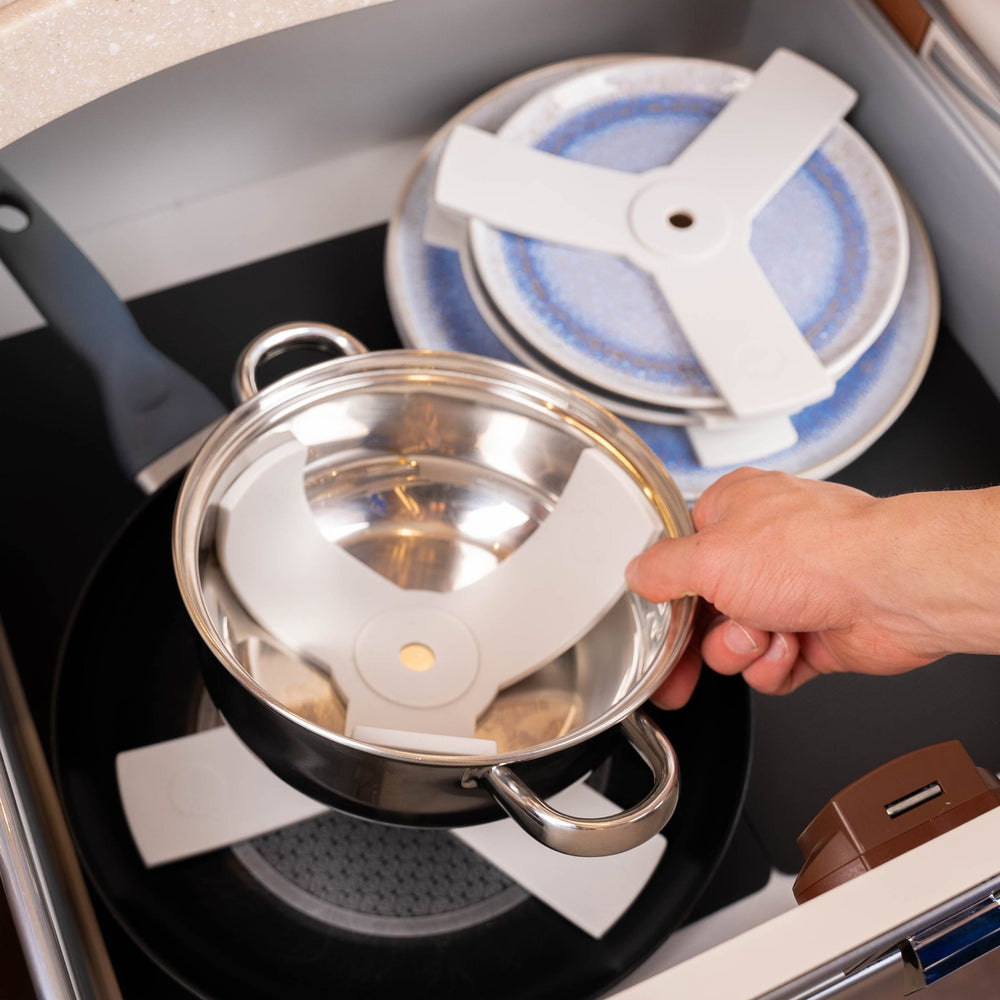 Silwy magnetic dish protectors securing stacked plates and a saucepan in an RV cupboard