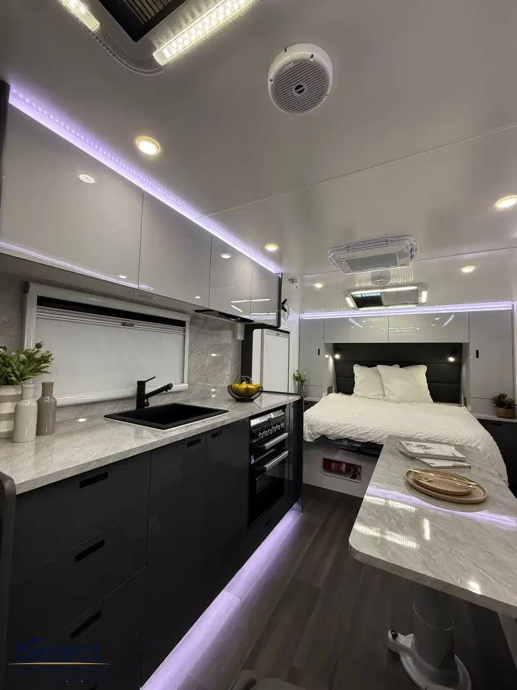 Modern kitchen and bedroom setup with a bed, kitchen counter, and sink.