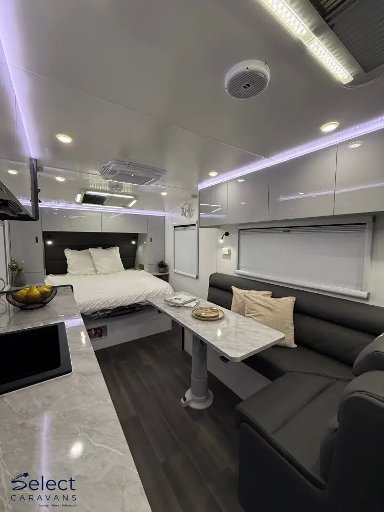 Modern interior of a vehicle with a bed, sofa, and small table.
