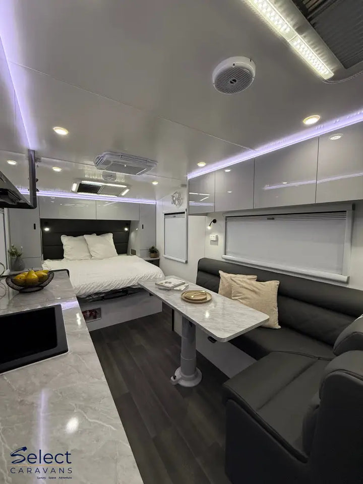 Modern interior of a vehicle with a bed, sofa, and small table.
