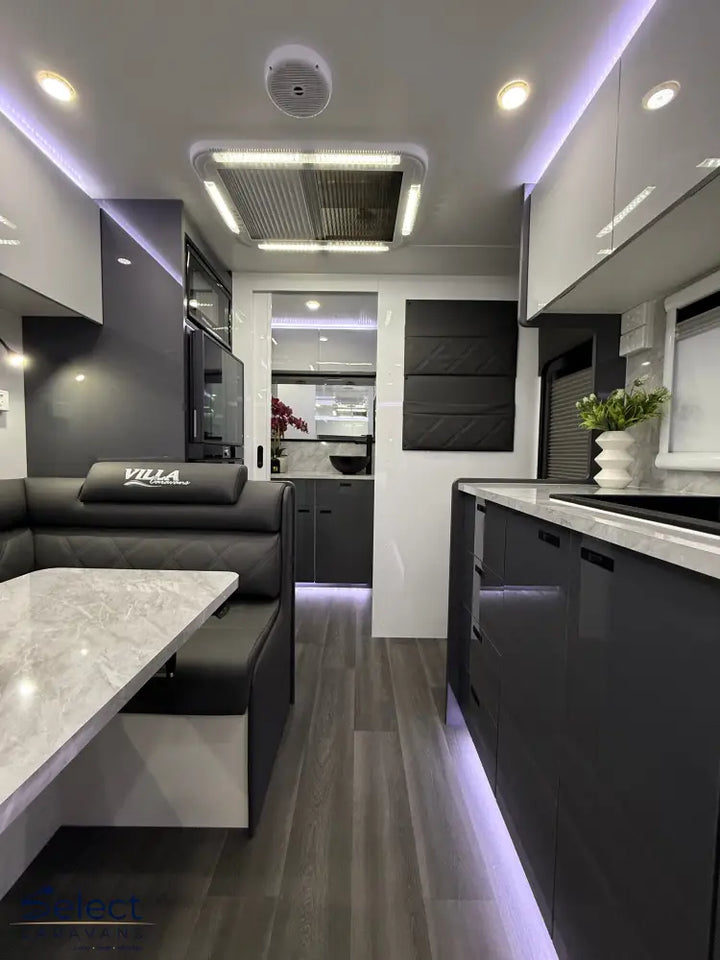 Modern kitchen and living area interior with gray furniture and white countertops.