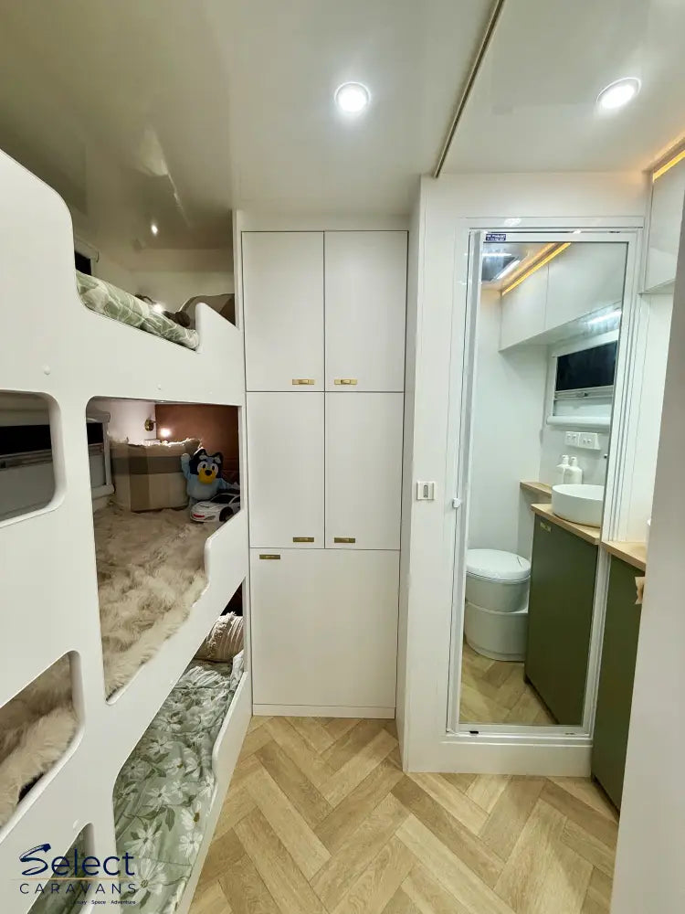 Small living space with bunk beds, cabinets, and a bathroom reflection in a mirror.
