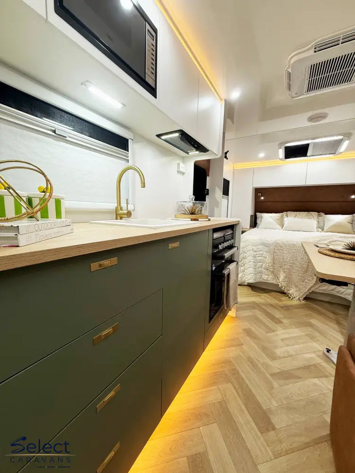 Modern kitchen with olive green cabinets and a bed in the background