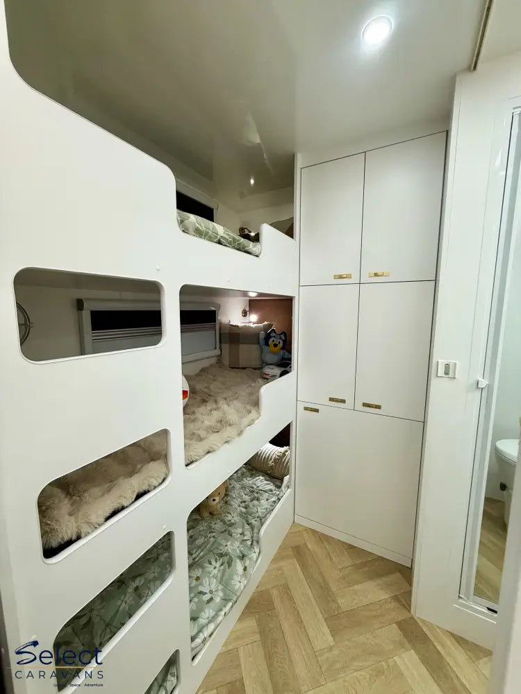 Triple Bunk beds in a compact living space with cabinets and a mirror.