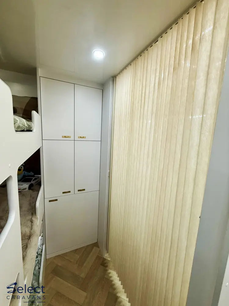 Children's room with bunk bed, white wardrobe, and beige curtain.