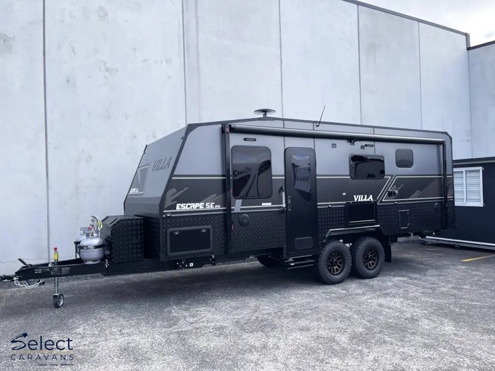Black Villa caravan parked in front of a gray building