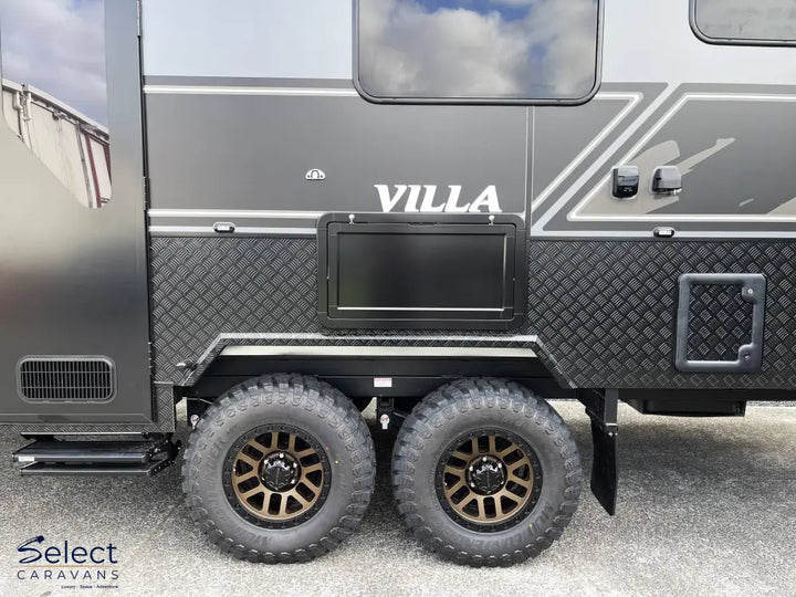 Black and gray caravan with 'Villa' branding on a cloudy day
